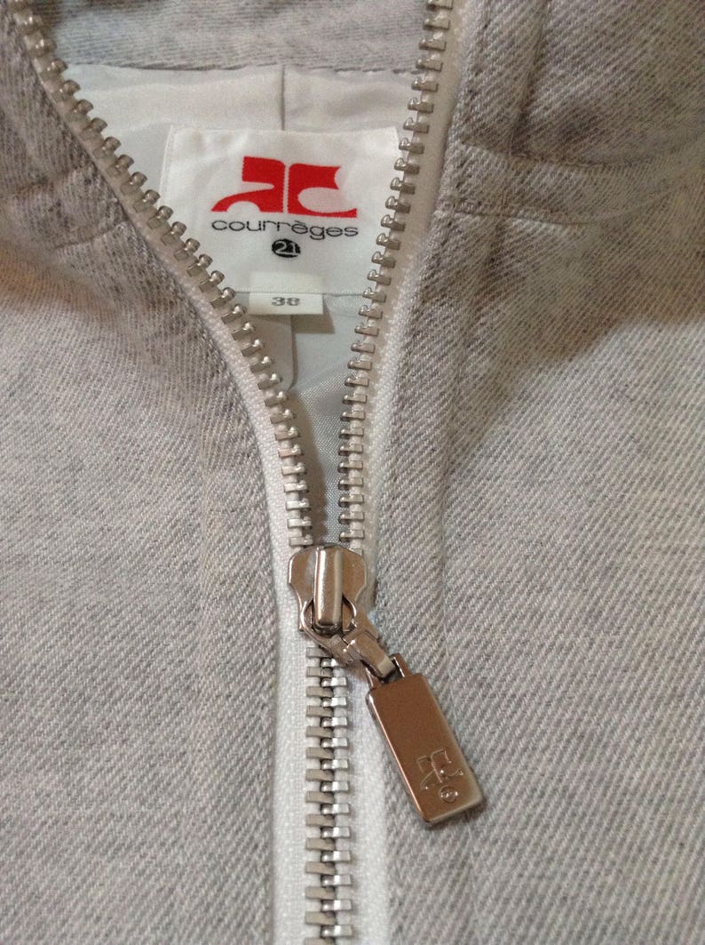 May include: A grey zipped hoodie with a white label that says "Courr&egrave;ges 21" and a silver zipper pull with the "Courr&egrave;ges" logo.