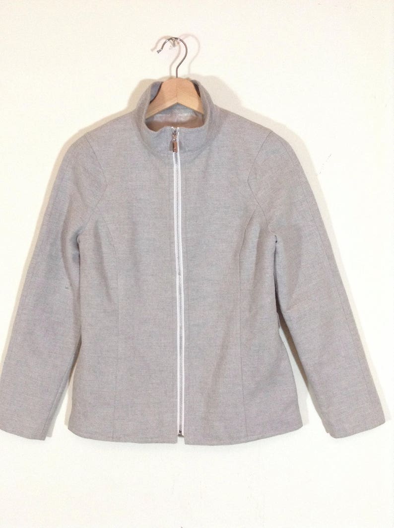 May include: A grey zip-up jacket with a white zipper.