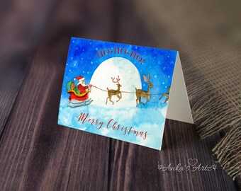 May include: Watercolor Christmas card featuring Santa Claus in a red sleigh pulled by reindeer against a blue night sky with a full moon. The card reads "Ho-Ho-Ho!" and "Merry Christmas" in red script.