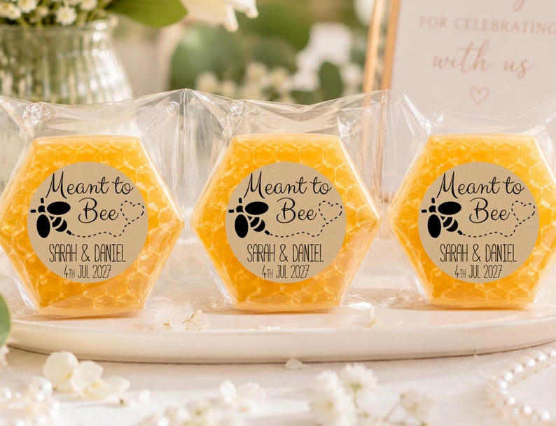 May include: Three hexagonal yellow soaps wrapped in clear plastic, each featuring a circular label with a black bee graphic, the text Meant to Bee, and the names Sarah & Daniel with the date 4th Jul 2027 printed in a clear, dark font.