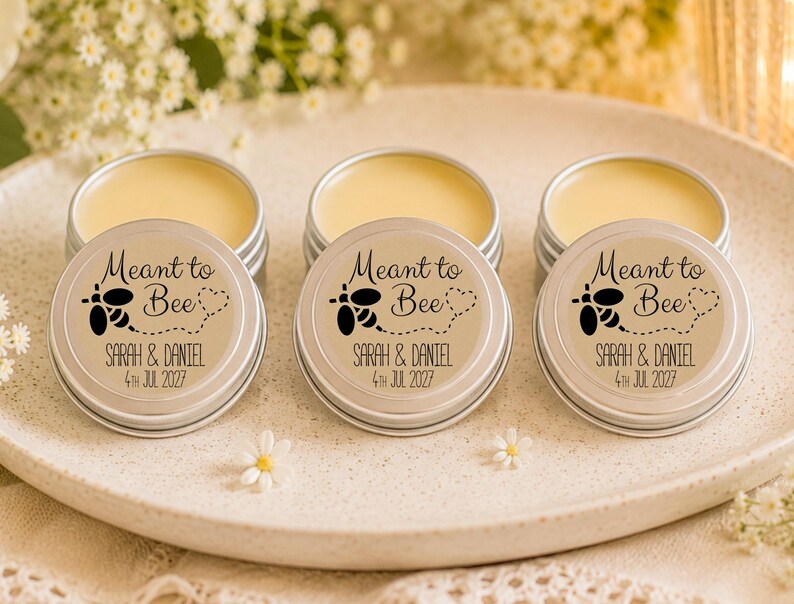 May include: Three round silver metal tins containing yellow lip balm. Each lid features a black graphic of a bee with a dotted flight path, the text "Meant to Bee", and the personalized names "Sarah & Daniel" with the date "4th Jul 2027".