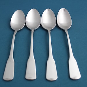 May include: Four silver spoons with rounded bowls and long handles. The spoons are arranged in a row on a blue background.