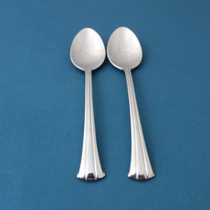 May include: Two silver spoons with a simple, elegant design. The spoons have a rounded bowl and a long, slender handle.