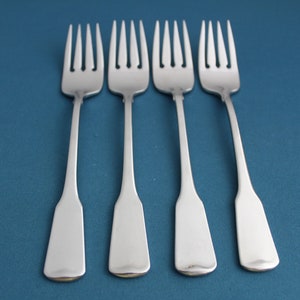 May include: Four silver dinner forks with a simple, elegant design. The forks have a smooth, polished finish and are arranged in a row on a blue background.