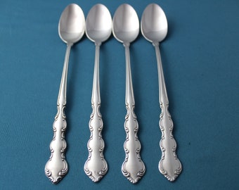 May include: Four silver spoons with ornate handles. The spoons are arranged in a row on a blue background.