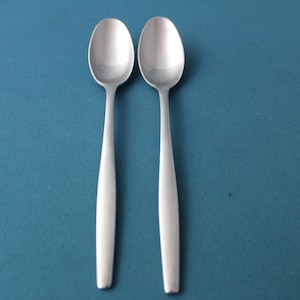 May include: Two silver spoons on a blue background.