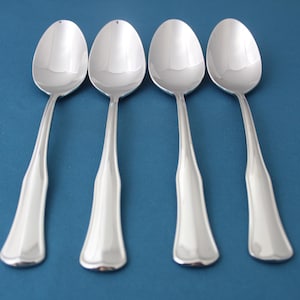 May include: Four silver spoons with a polished finish. The spoons have a rounded bowl and a long, slender handle.