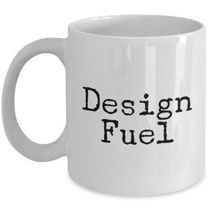May include: White ceramic coffee mug with black text that reads "Design Fuel".