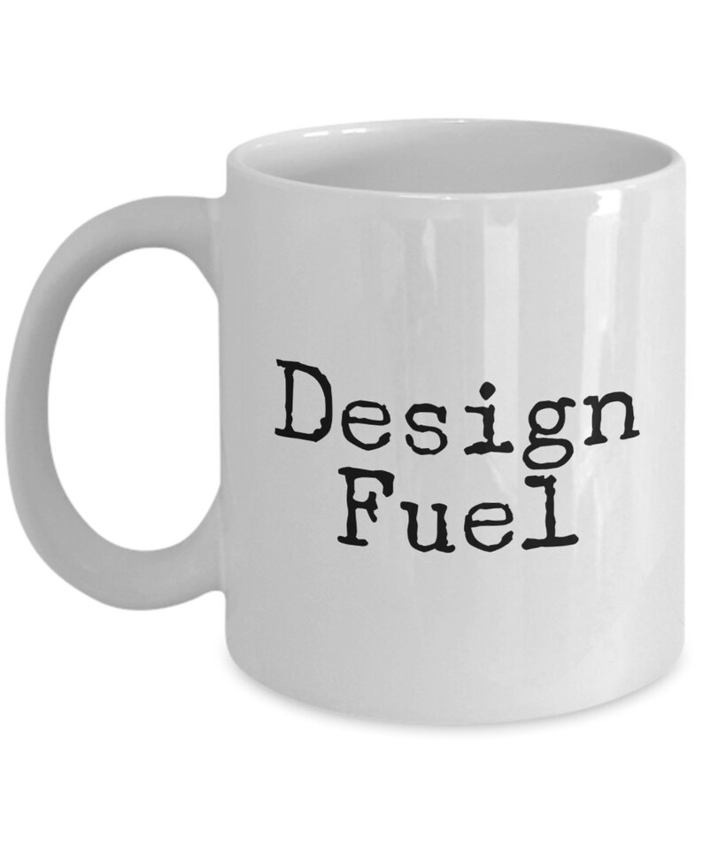 May include: White ceramic coffee mug with black text that reads "Design Fuel".