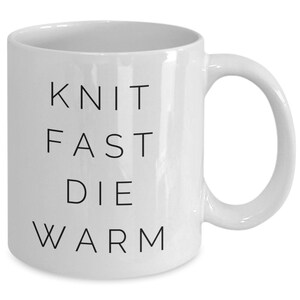 May include: White ceramic mug with black text that reads "Knit Fast Die Warm".