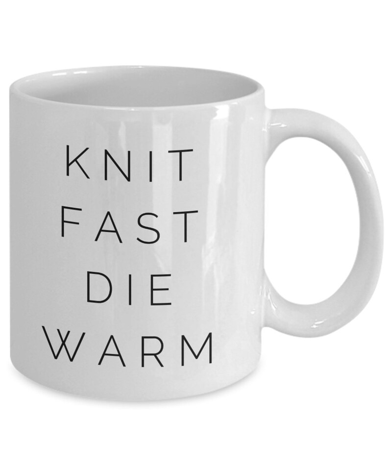 May include: White ceramic mug with black text that reads "Knit Fast Die Warm".