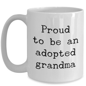 May include: White ceramic coffee mug with black text that reads "Proud to be an adopted grandma".
