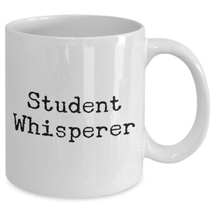 May include: White ceramic coffee mug with black text that reads "Student Whisperer".