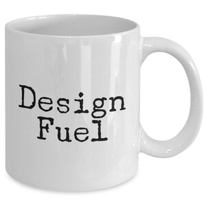 May include: White ceramic coffee mug with black text that reads "Design Fuel".