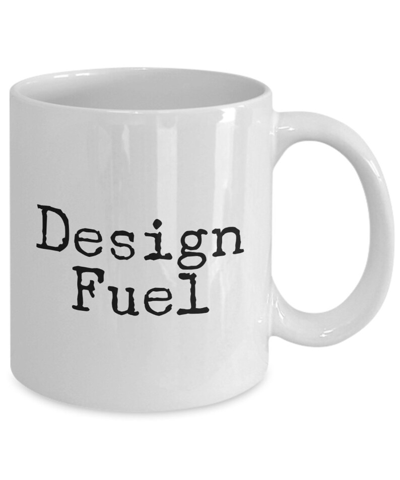 May include: White ceramic coffee mug with black text that reads "Design Fuel".