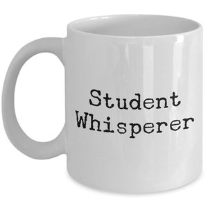May include: White ceramic coffee mug with black text that reads "Student Whisperer".