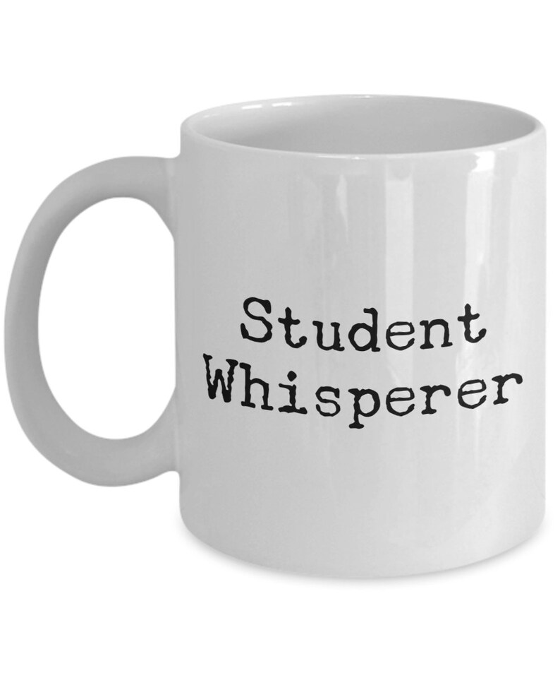 May include: White ceramic coffee mug with black text that reads "Student Whisperer".