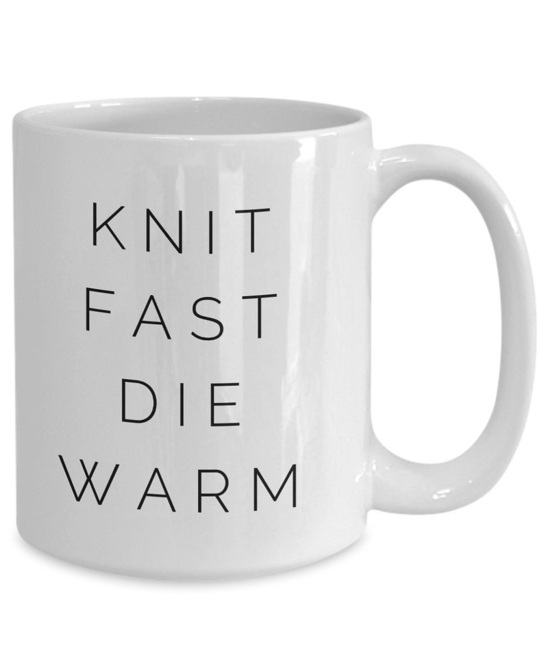May include: White ceramic coffee mug with black text that reads "Knit Fast Die Warm".