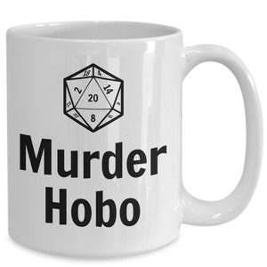 K&ouml;nnte beinhalten: Wei&szlig;e Keramiktasse mit einer Schwarzwei&szlig;illustration eines zwanzigseitigen W&uuml;rfels und dem Text "Murder Hobo".