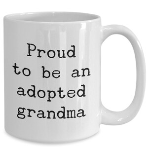 May include: White ceramic coffee mug with black text that reads "Proud to be an adopted grandma".