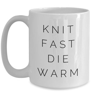 May include: White ceramic mug with black text that reads "Knit Fast Die Warm".