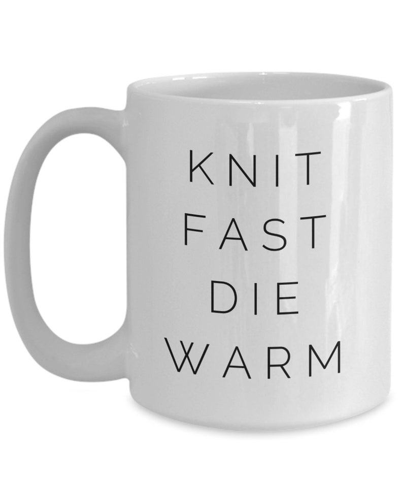 May include: White ceramic mug with black text that reads "Knit Fast Die Warm".