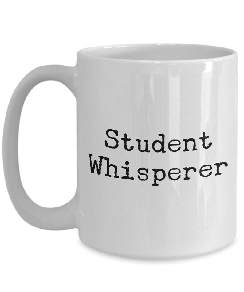May include: White ceramic coffee mug with a black inscription that reads "Student Whisperer".