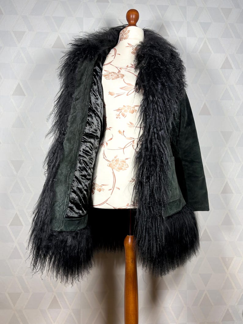 May include: A black suede coat with a long, fluffy black fur collar and trim. The coat is lined with a black satin fabric.