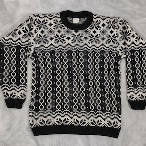 May include: Black and white knitted sweater with a snowflake pattern.