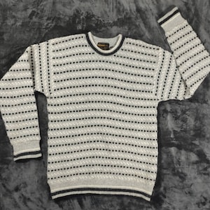 May include: A grey and black striped sweater with a crew neck and long sleeves. The sweater has a small label that says "Bottega" on the front.