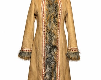 May include: A tan long coat featuring a hood and trim made of brown and gray faux fur. The coat includes decorative vertical bands with red and white wavy line patterns along the front opening, cuffs, and hemline.