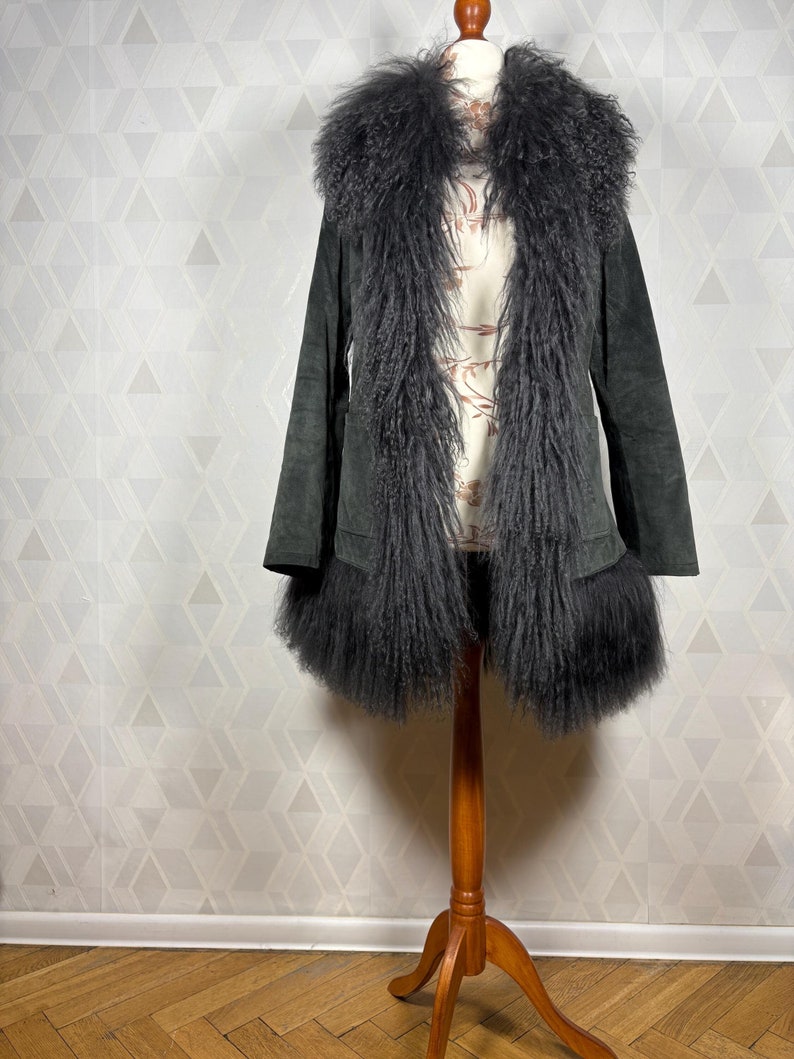 May include: A dark green suede jacket with a large, fluffy gray faux fur collar and cuffs.