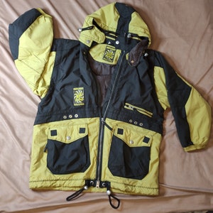 May include: A black and yellow ski jacket with a hood. The jacket has a zipper closure and two large pockets on the front. The jacket has the words "Killtec" and "Highlight" on the front.