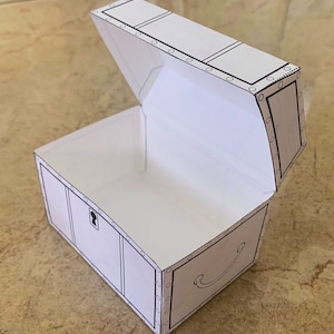 Puede incluir: Un cofre del tesoro de papel blanco con un contorno negro y una cerradura. La tapa est&aacute; abierta y el cofre est&aacute; vac&iacute;o.