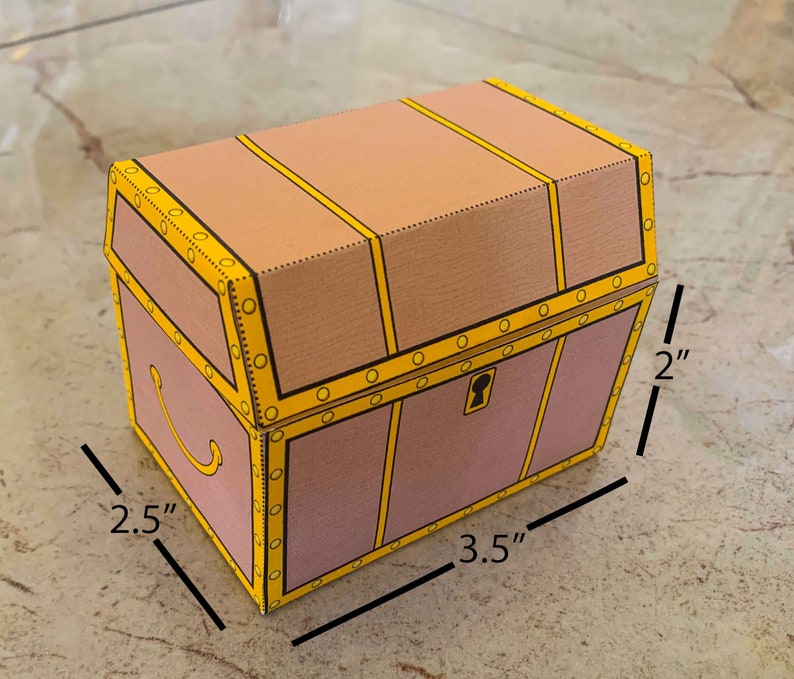 Puede incluir: Un cofre del tesoro de cart&oacute;n con un dise&ntilde;o marr&oacute;n y amarillo. El cofre mide 2,5 pulgadas de ancho, 3,5 pulgadas de largo y 2 pulgadas de alto.