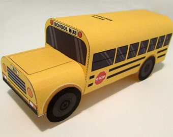 Peut inclure: Un modèle de bus scolaire en papier jaune avec des rayures noires, un panneau d'arrêt rouge et l'inscription "School Bus" sur le côté.