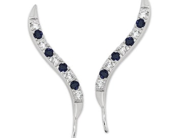 Puede incluir: Un par de pendientes de plata con un diseño curvo. Los pendientes están adornados con pequeños diamantes transparentes y zafiros azules.