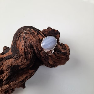 Op de afbeelding: Een zilveren ring met een lichtblauwe agaat-steen. De steen heeft een gebandeerd patroon en is gezet in een eenvoudige ovale zetting.