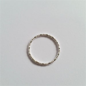 May include: A silver ring with a beaded design. The ring is made of a thin band of metal with small, round beads evenly spaced around the band.