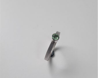 May include: A silver ring with a light green gemstone.