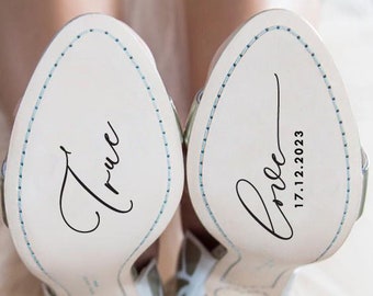 May include: A pair of white wedding shoes with a butterfly design. The soles of the shoes are personalized with the words "True" and "Love 17.12.2023".