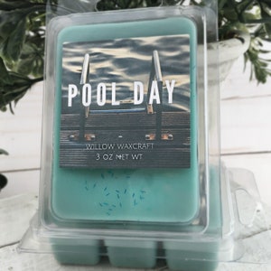 May include: A teal-colored wax melt in a clear plastic clamshell container. The label reads "POOL DAY" with an image of a pool. The product is from Willow Waxcraft and weighs 3 oz.