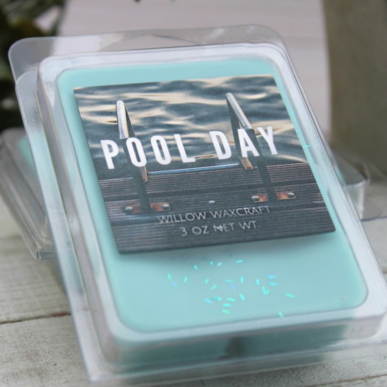 May include: A teal-colored wax melt in a clear plastic clamshell container. The label reads "POOL DAY" with an image of a pool. The product is labeled "Willow Waxcraft 3 OZ NET WT".