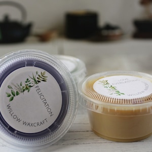 May include: Two small containers of wax melts, one purple and one beige. The containers have white labels with green foliage and the text "Willow Waxcraft" and "Felicitatiion" or "Love Everlasting".