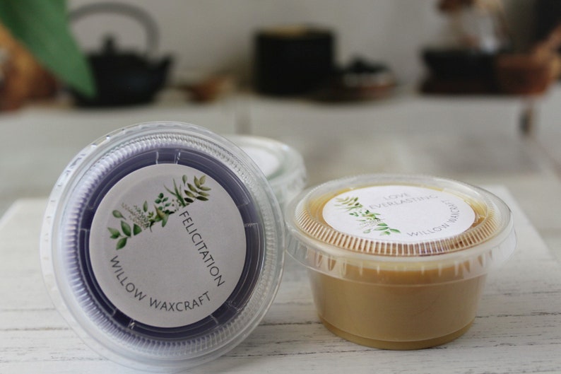 May include: Two small containers of wax melts, one purple and one beige. The containers have white labels with green foliage and the text "Willow Waxcraft" and "Felicitatiion" or "Love Everlasting".