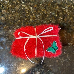 May include: A red, fuzzy gift bag with a white ribbon and a green butterfly applique.