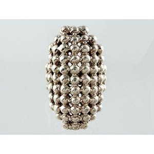 May include: A silver-toned ring featuring a wide, elongated band constructed from a dense, interconnected grid of small, polished spherical beads. The design creates a textured, lattice-like appearance with a reflective metallic finish throughout.