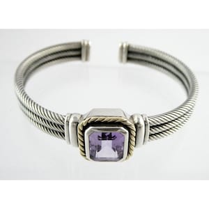 May include: A silver and gold bangle bracelet with a purple amethyst gemstone set in a square frame.