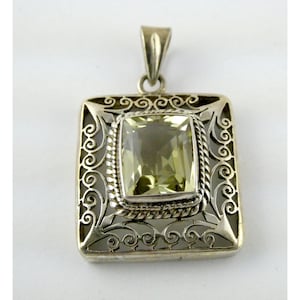 May include: A square silver pendant with a light green gemstone center. The pendant has an ornate filigree design around the gemstone and along the edges. The bail is a simple, solid silver loop.