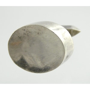 May include: A silver-colored, round, flat-bottomed object with a slightly raised edge. The object is smooth and appears to be made of metal.